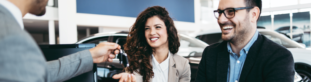 Happy customers at Wyatt Johnson Toyota being handed keys to a new car.