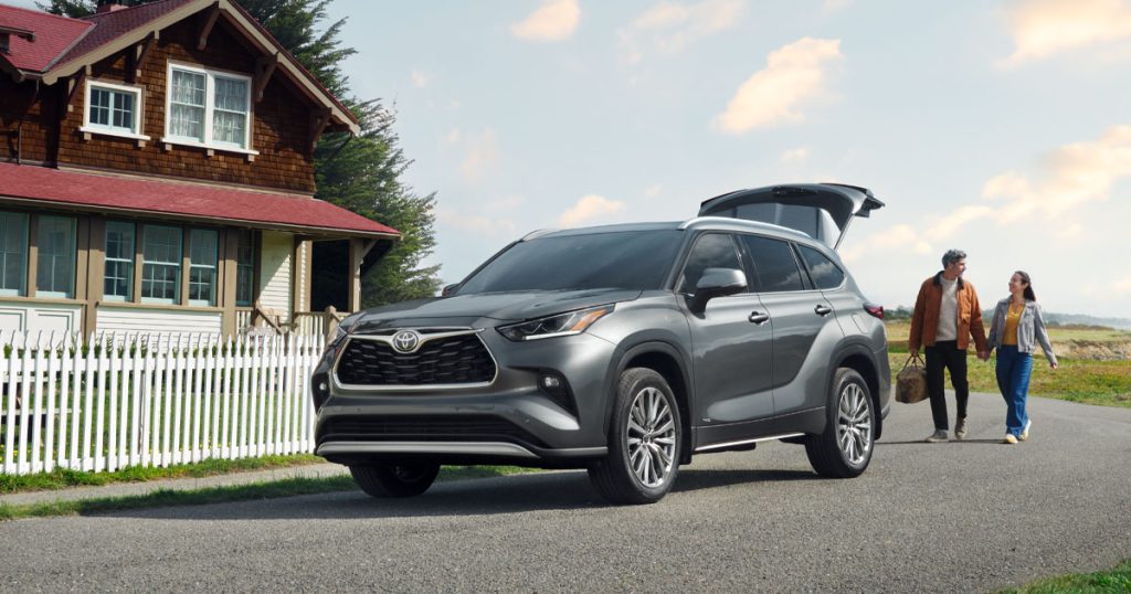 A couple packing their Toyota Highlander in front of a house.