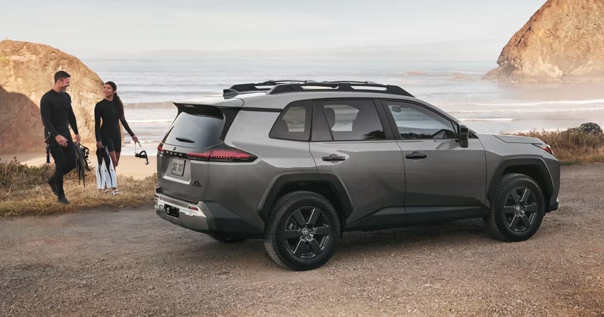 A couple walking towards their Toyota vehicle on a beach setting.